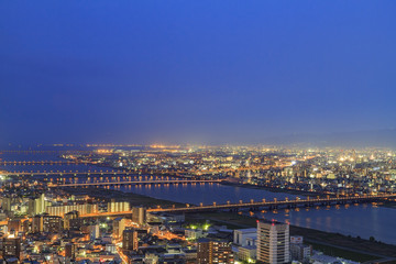 Night scene of Osaka downtown with buildings, river and bridge