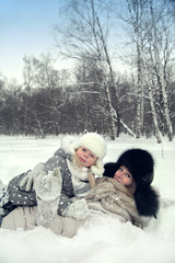 Attractive family mother and daughter lay on a snow in a winter park