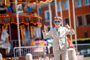 Stylish kid near the traditional French merry-go-round showing thumbs up, Beauvais, France