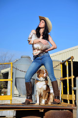 Cowgirl holding a little lamb and dog guards them