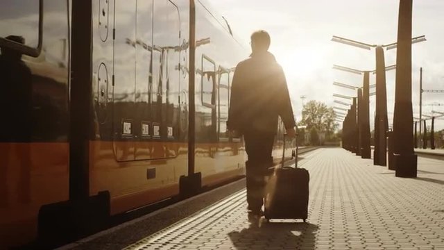 Confident Man With Luggage Walking on Railway Station at Sunset Time. Shot on RED Cinema Camera.