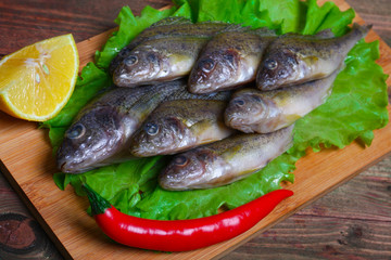 raw redfish ruff fish on the kitchen table with vegetables and lemon