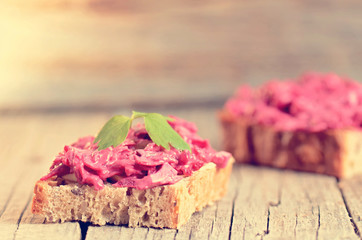 Two slices of bread on a wooden table with beetroot spread. Natural background and healthy, vegetarian and vegan food. Fast breakfast. Raw food. Agriculture