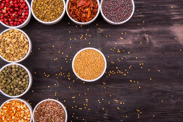 Специи в белых плошках на темной деревянной доске