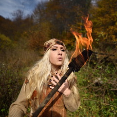 Beautiful young woman outdoor on autumn day holding burning torc