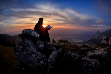 silhouette of priest reading in the sunset light, Romania, Ceahl