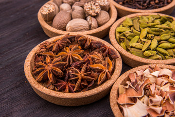 Специи в круглых формах на темной деревянной доске