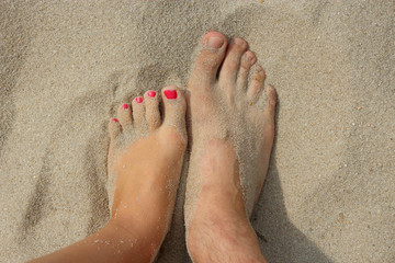 feet of father and his teen daughter on the sand