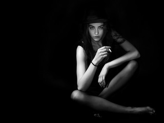 Transgressive girl portrait sitting and smoking cigarette black and white