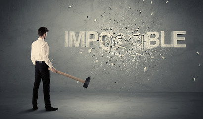 Business man hitting impossible sign with hammer