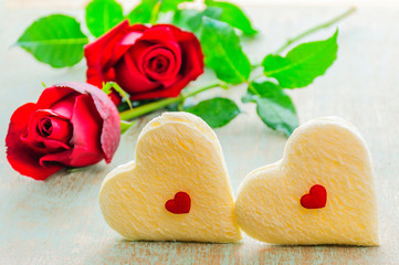Couple of heart shape white bread and red rose. Photo is focused at the bread.