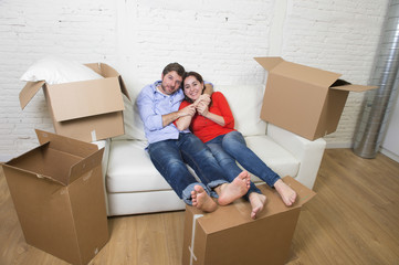 Fototapeta na wymiar young happy American couple lying on couch together celebrating moving to new house unpacking cardboard boxes