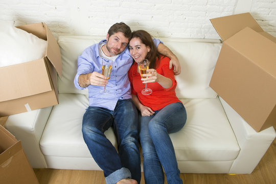  young happy American couple lying on couch together celebrating moving to new house unpacking cardboard boxes