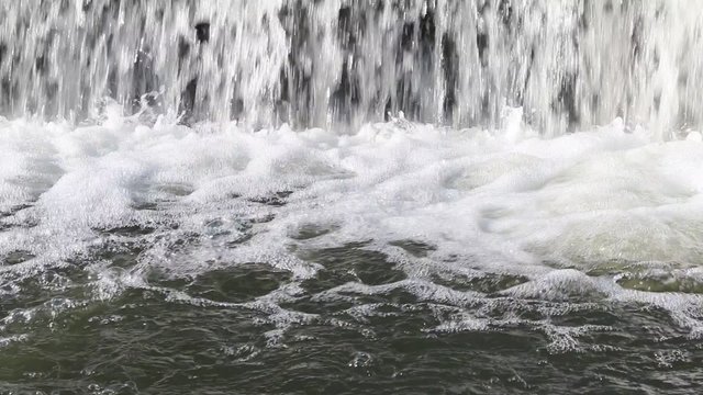 Pure fresh water boiling under waterfall. Clean and clear water in trout river with reflecting sunrays. 