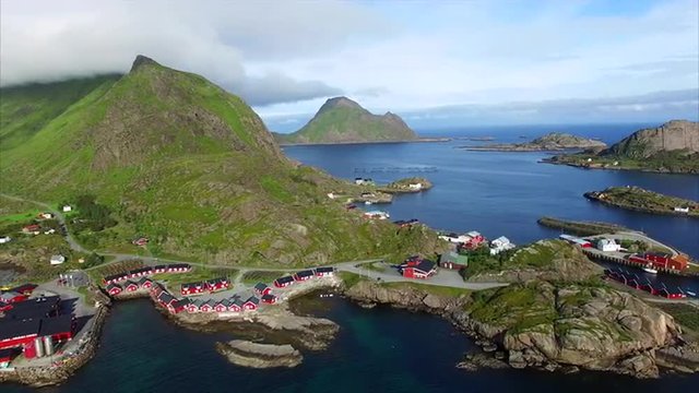 Aerial footage of former fishing port Mortsund with red rorbu fishing huts currently used as tourist resort on Lofoten islands in Norway, popular with tourists for natural beauty. Aerial 4k Ultra HD.
