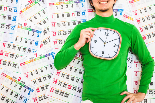 大きな掛け時計を男性持っている男性,緑の服