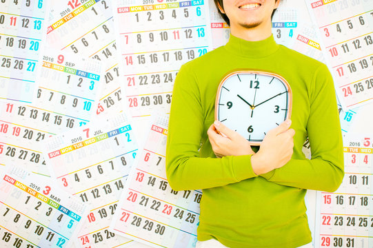 大きな掛け時計を男性持っている男性,緑の服