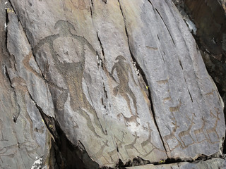 Prehistorical people and animals petroglyphs carved in stones