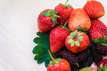 Mulberry with strawberry on wooden table