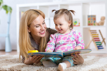 happy mother read a book to child girl indoors