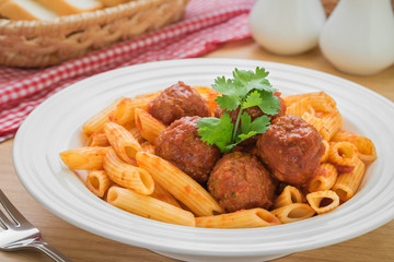 Penne pasta with meatballs in tomato sauce on plate 
