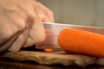 Chef peeling carrot with Knife.
