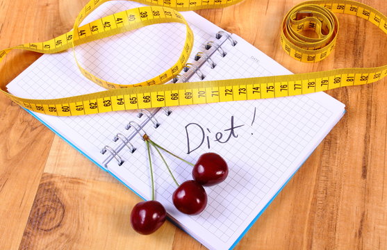 Cherry and centimeter with notebook, slimming and healthy food