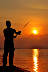 Silhouette Man fishing on a lake at sunset