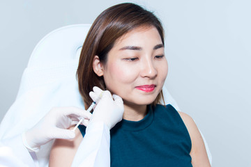 Cosmetologist giving Asian woman injection with syringe