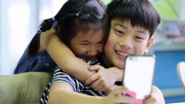 Little asian boy and girl take a photo with cell phone