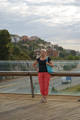 Aged lady is standing on footbridge in Santa Susanna, Spain.
