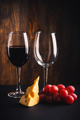 Two glasses, a pice of cheese and bunch of grapes