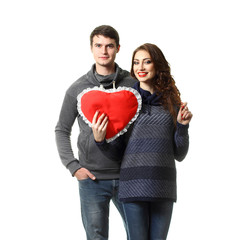Ordinary beautiful couple having fun with a pillow in the form of heart on Valentine's Day. On a white background.