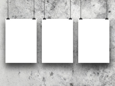 Close-up of three hanged paper sheet frames with clips on weathered concrete wall background