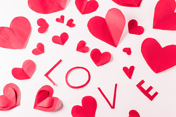 Red paper hearts made of Valentines Day confetti on white background.