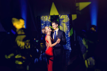 stylish luxury bride in red dress and groom dancing in a restaur