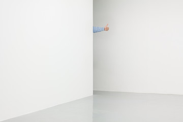 White walls corner with male hand showing ok