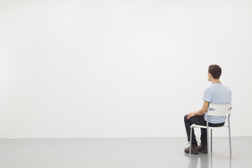 Man sitting on a chair in white room