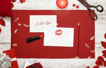 Making I love you message and envelope with imprint of a kiss surrounded with petals, rose, gift, candle, carmine, pencil  on wooden table