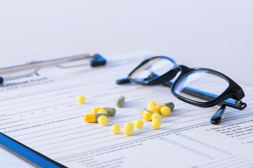 Pills and glasses on top of hospital form. 