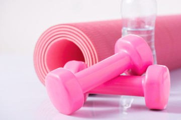 Yoga mat with dumbbells and bottle of water.