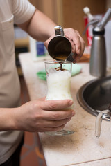 Barista pouring milk in capuccino coffee in coffeeshop