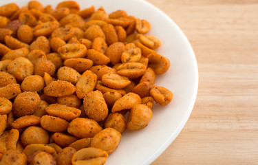 Plate of hot and spicy peanuts on a wood table