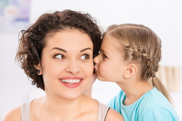 Daughter is kissing her smiling mother.