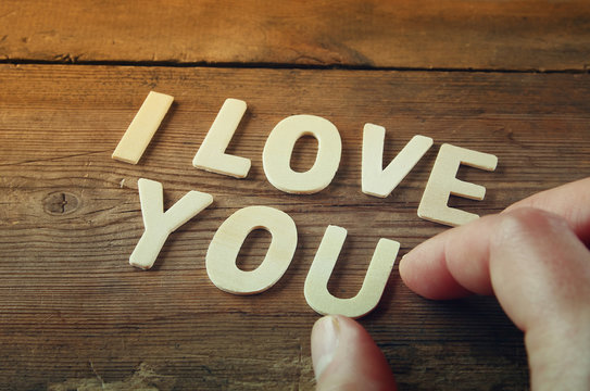 selective focus photo of The words "i love you" made with block wooden letters on wooden background. valentine's day celebration concept. vintage filtered and toned