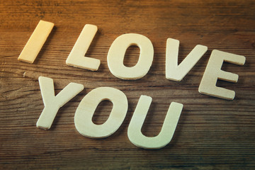 selective focus photo of The words "i love you" made with block wooden letters on wooden background.  valentine's day celebration concept. vintage filtered and toned