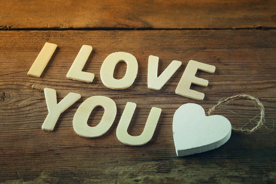 selective focus photo of The words "i love you" made with block wooden letters on wooden background.  valentine's day celebration concept. vintage filtered and toned