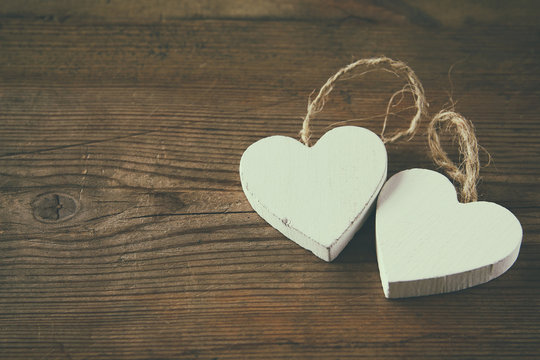 selective focus photo of couple of wooden hearts on rustic table.  valentine's day celebration concept. vintage filtered