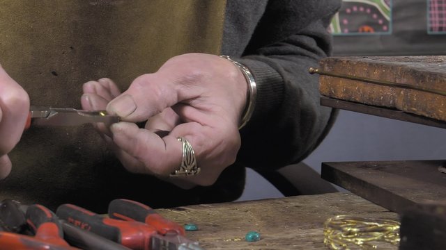 a craftsman jeweler creates a bracelet