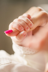 Newborn baby holding mother's finger